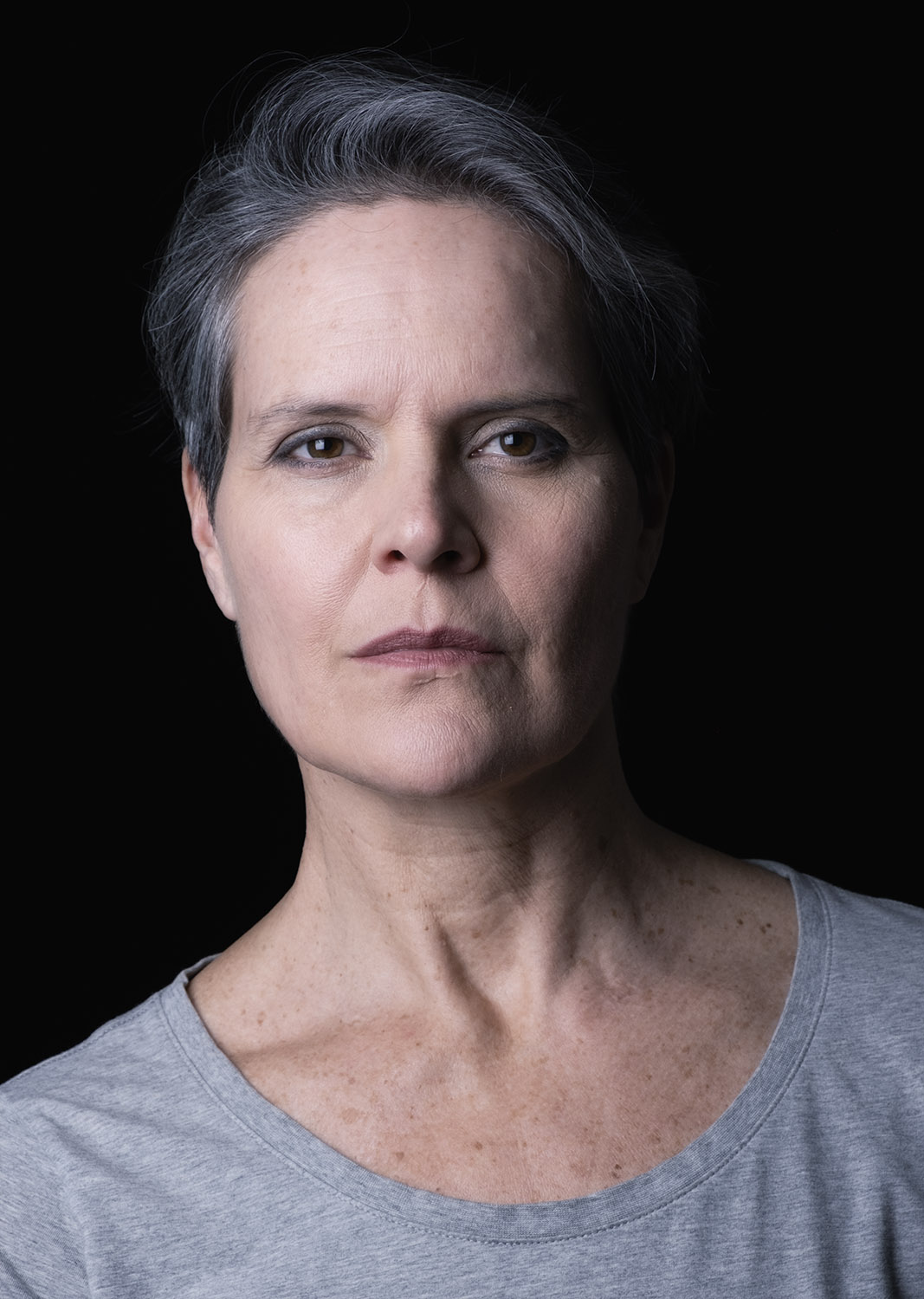 Portrait photography of mature woman headshot grey hair black background